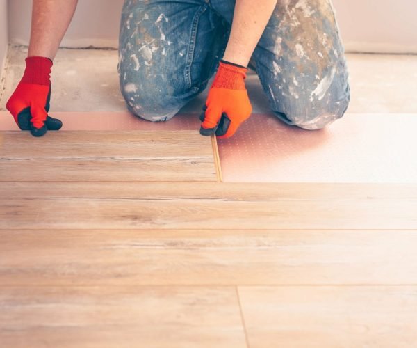 Professional installation of floor covering, the worker quickly and qualitatively mounts a laminate board